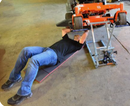 A man is lying down on the mat to repair the machine